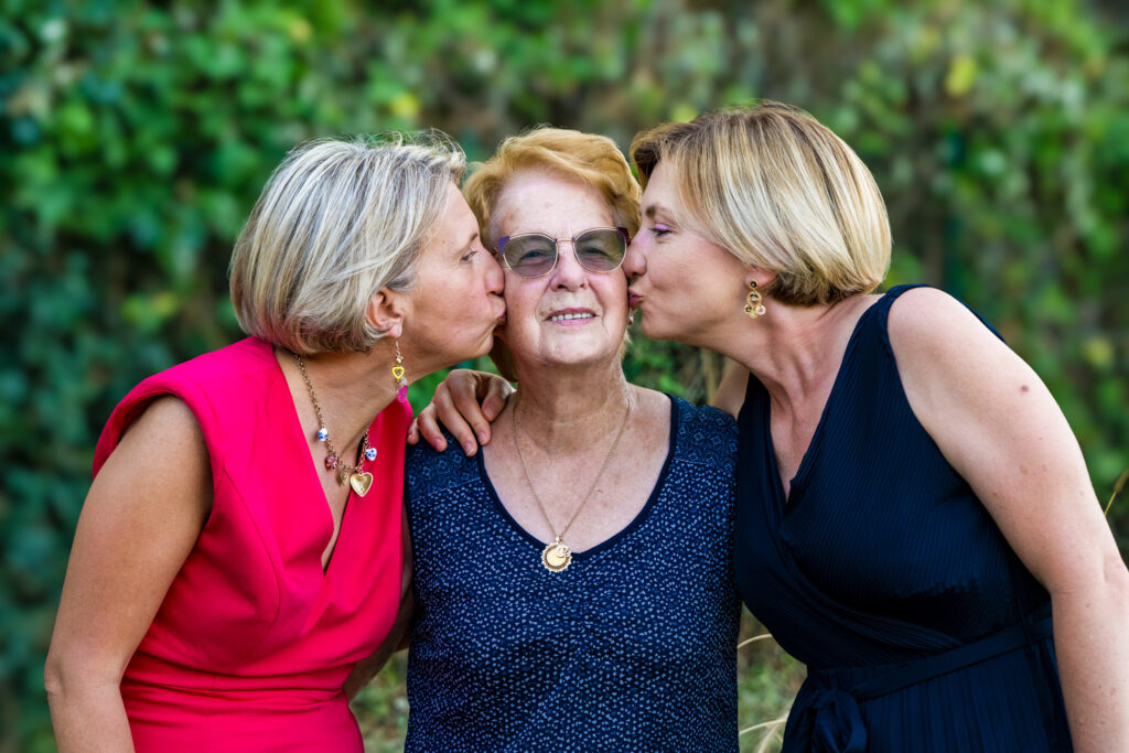 Deux femmes embrassant leur mère avec affection pendant le mariage