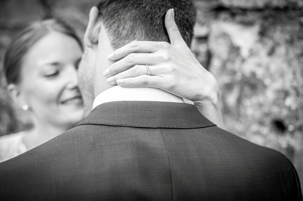 Main de la mariée montrant l'alliance sur l'épaule du marié