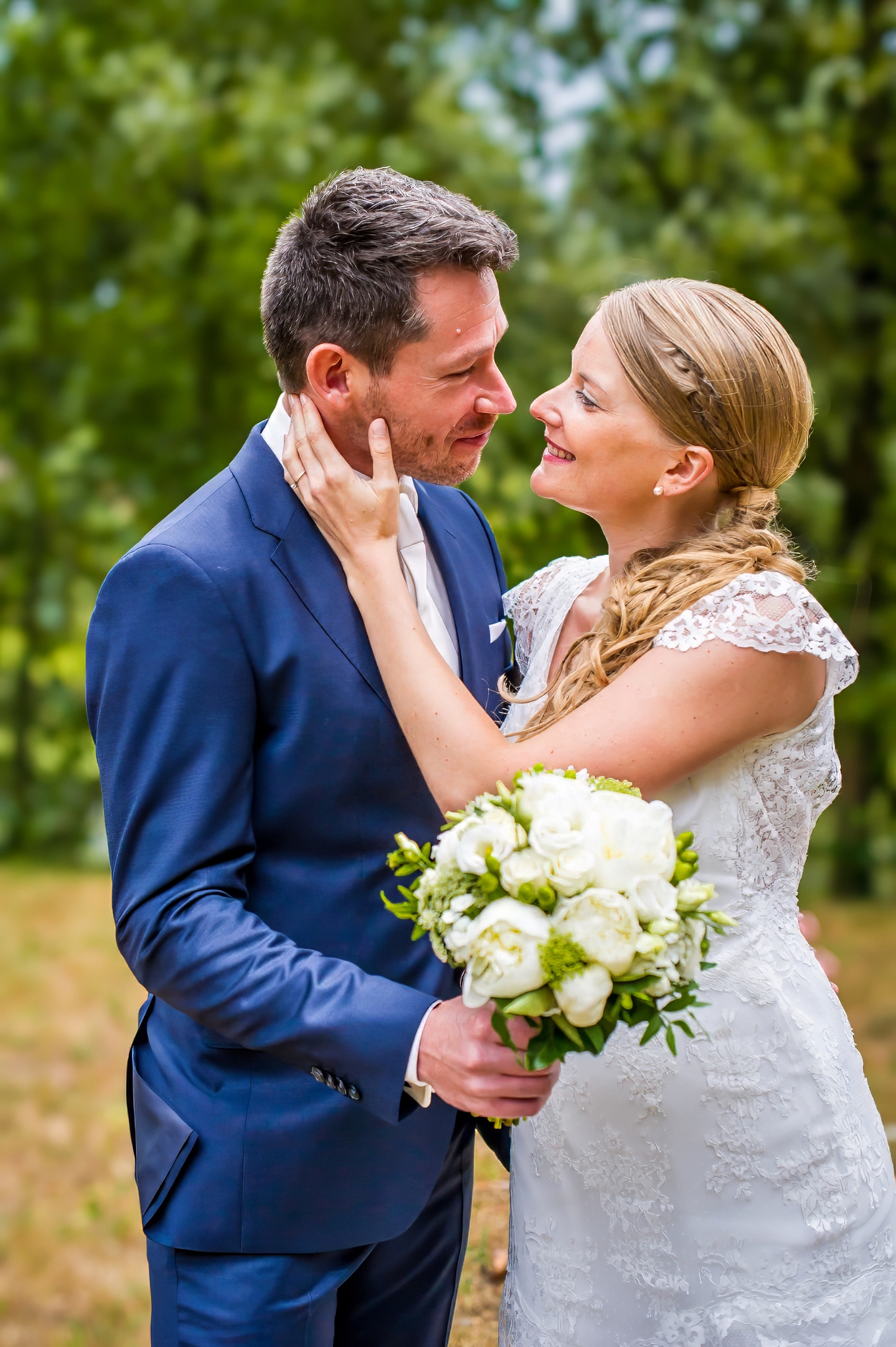 Couple de mariés se regardant avec amour, bouquet de fleurs en main