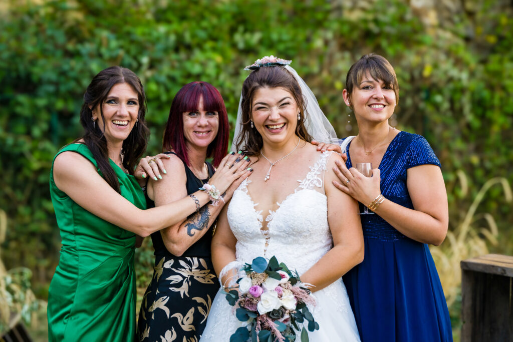 Mariée et ses amies posant ensemble avec leurs sourires au vin d'honneur du mariage