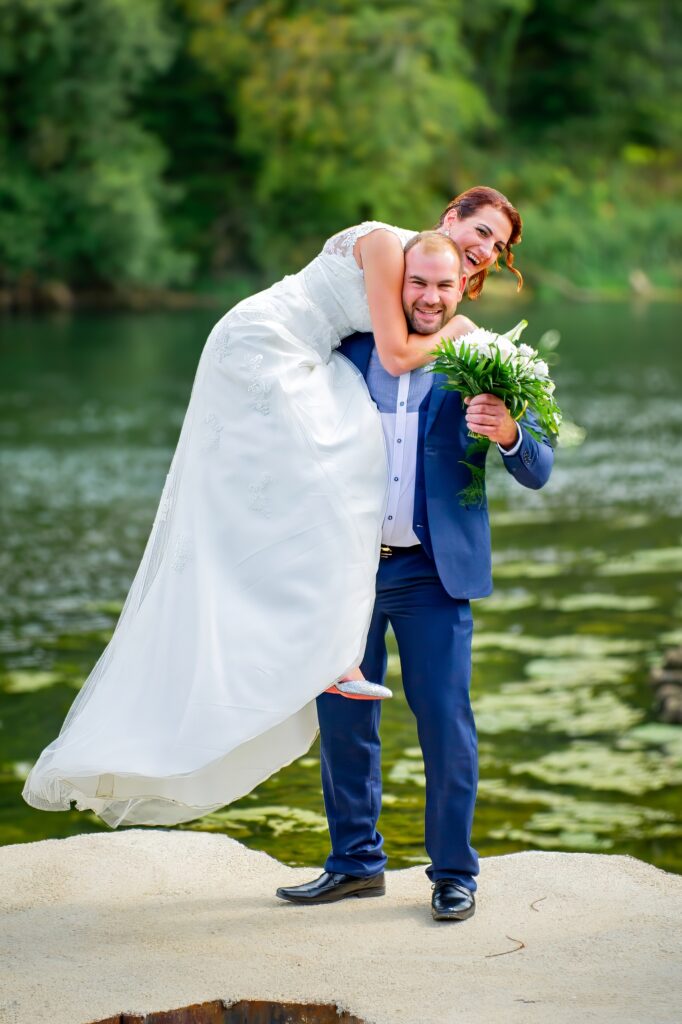 Mariée sur une épaule du marié tenant un bouquet