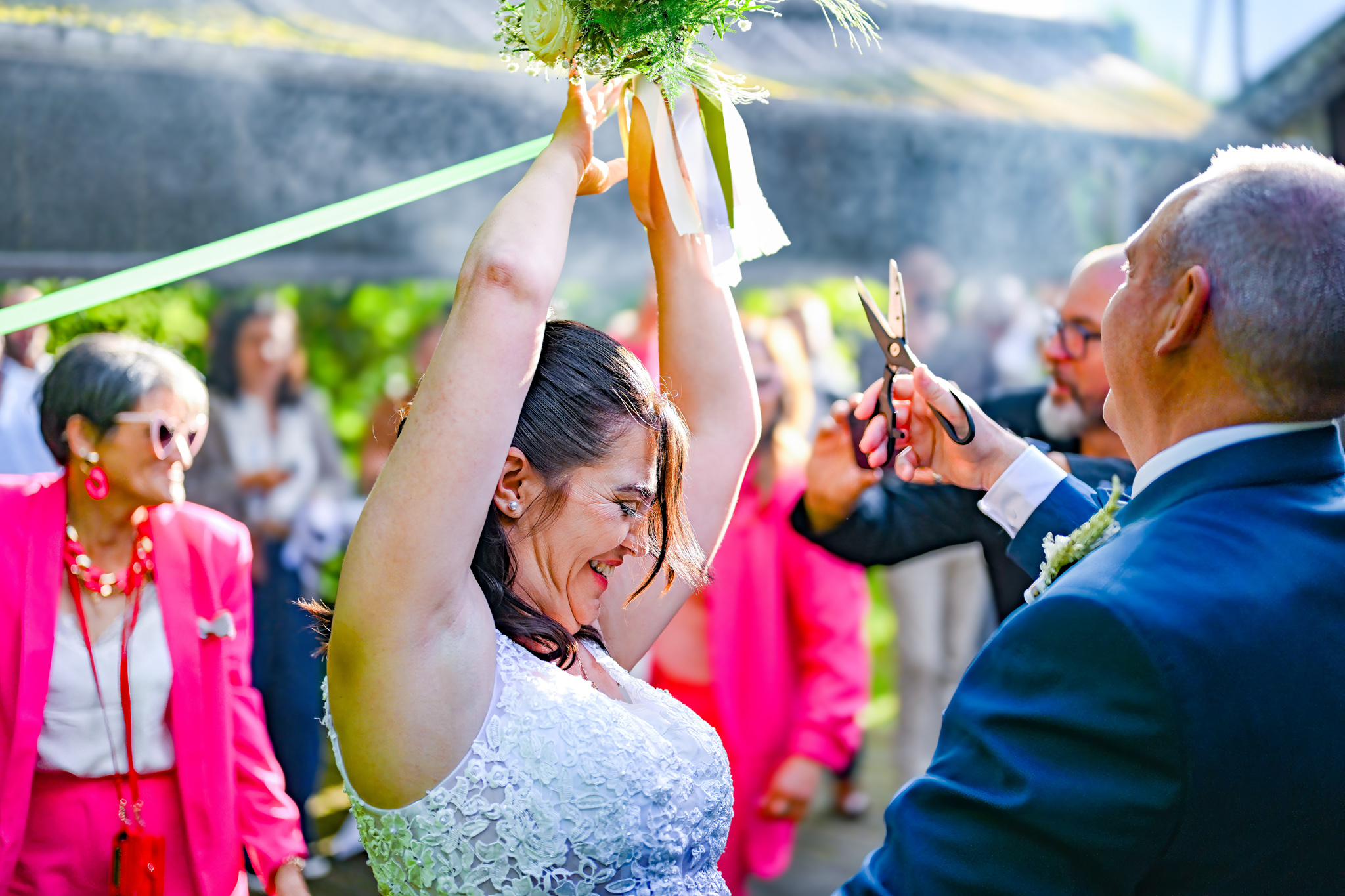 Mariée tenant le bouquet au-dessus de sa tête tandis que les invités coupent les rubans pendant le mariage