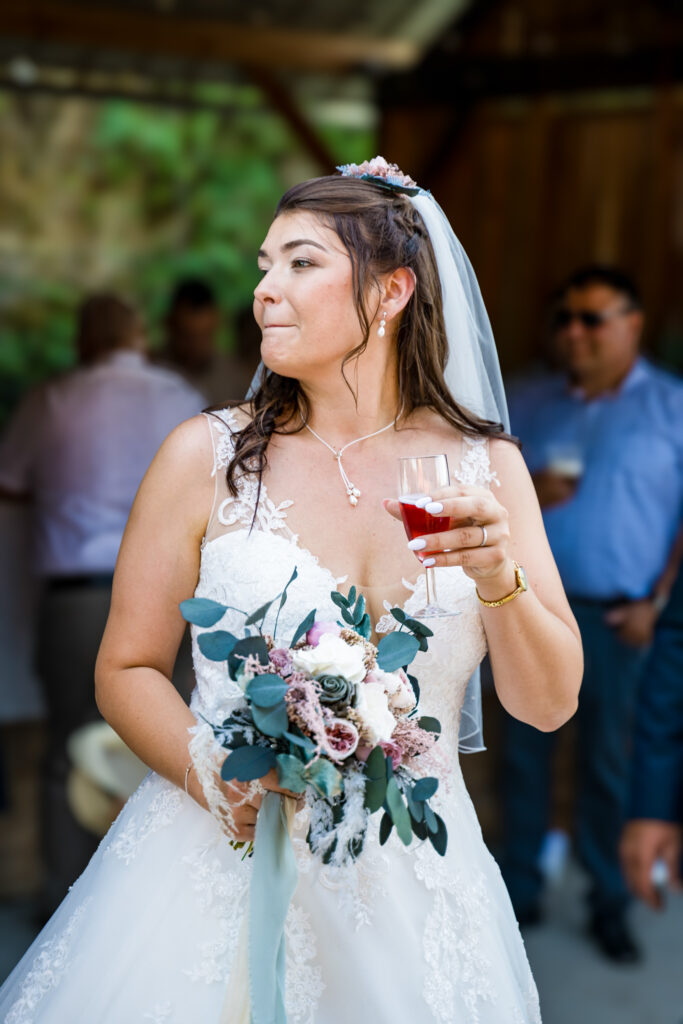 Mariée tenant son bouquet et son verre au vin d'honneur du mariage