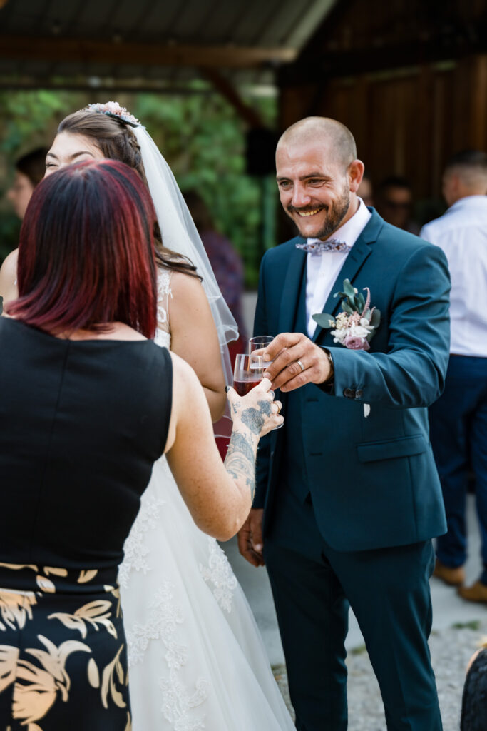 Marié et mariée levant le verre avec une invitée au vin d'honneur du mariage