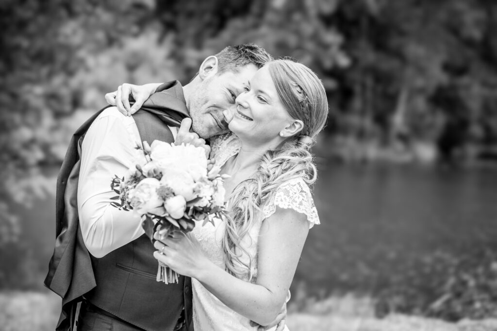 Mariés s'enlaçant avec un bouquet en noir et blanc