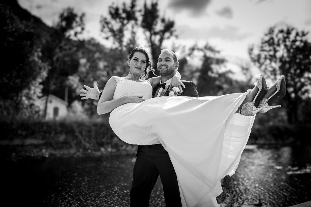 Marié portant la mariée devant un paysage en noir et blanc