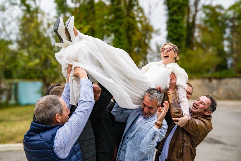 Invités portant la mariée en l'air pendant les célébrations du mariage