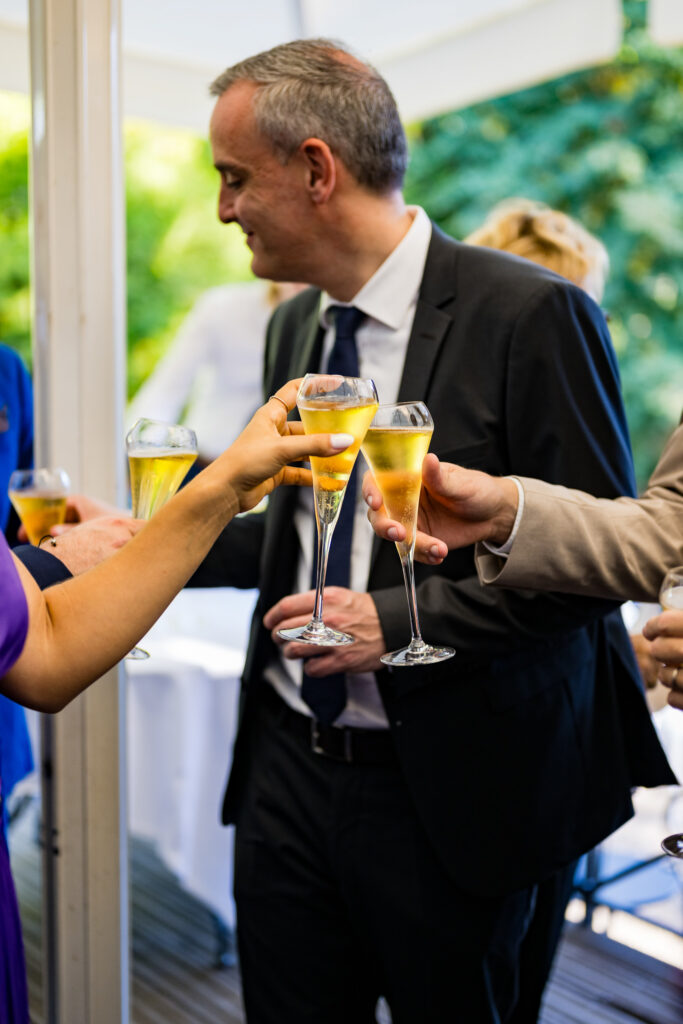 Invités portant un toast avec des verres de champagne pendant le vin d'honneur du mariage