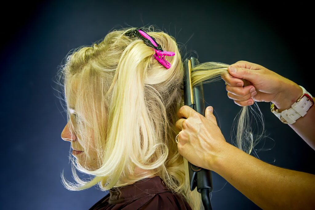 Mariée pendant le lissage de ses cheveux par une coiffeuse