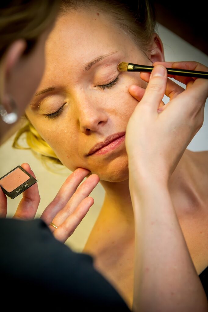 Retouche délicate du maquillage des paupières de la mariée avec les yeux fermés