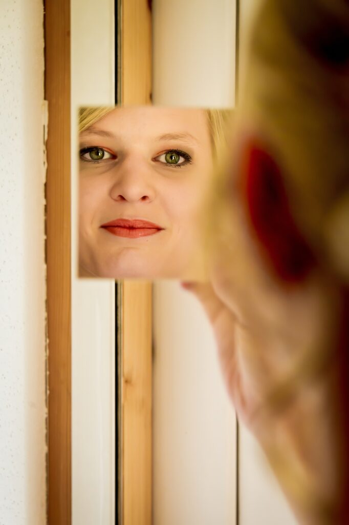 Mariée souriante se regardant dans un miroir de poche avec un fond en bois