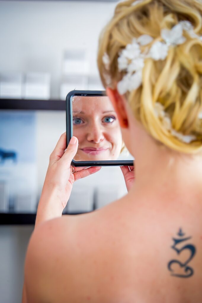 Mariée souriante se regardant dans un miroir en main