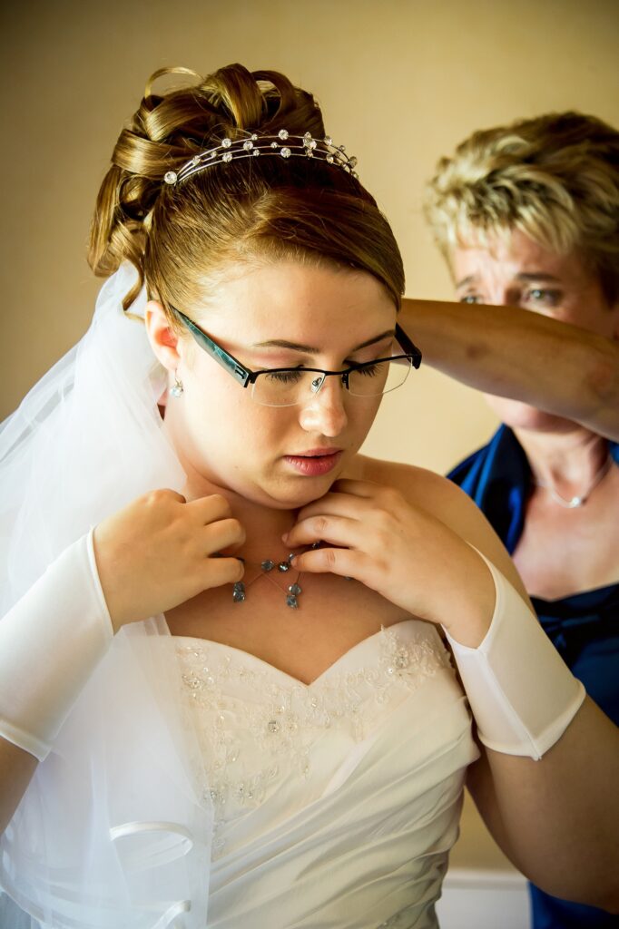 Préparatifs de la mariée ajustant un collier avec l'aide d'une autre personne