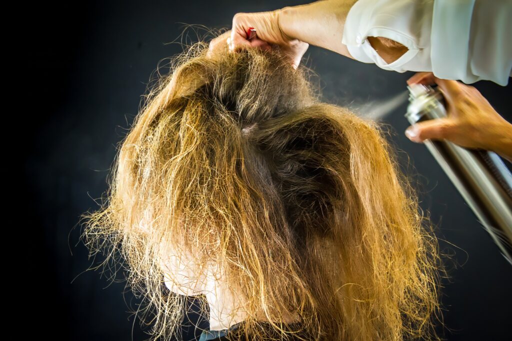 Coiffeuse utilisant un spray pour les cheveux sur les cheveux d'une mariée