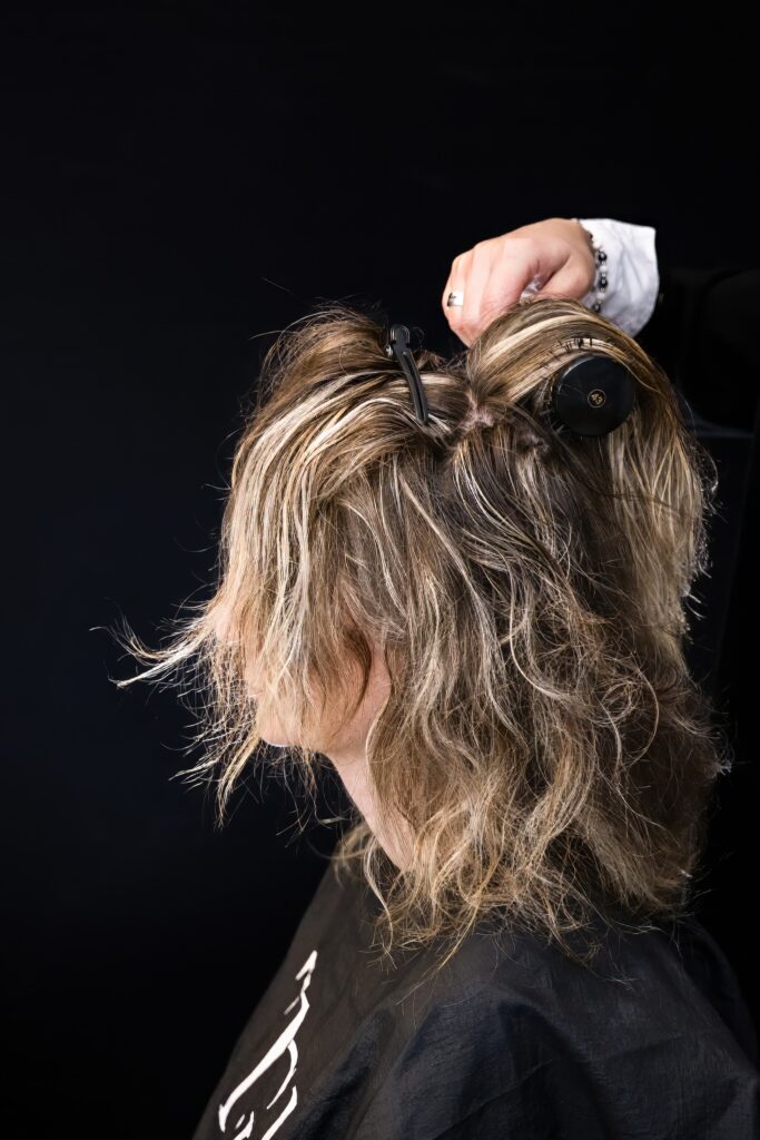 Coiffeuse utilisant une brosse ronde sur les cheveux mouillés d'une mariée