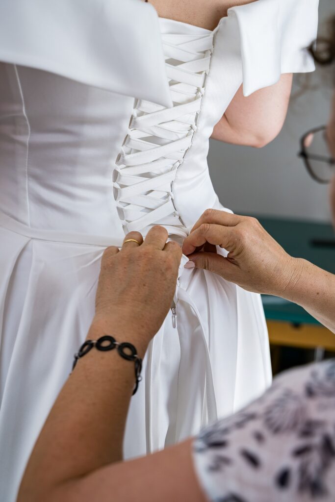 Sa maman ajustant le corset de la robe de la mariée blanche